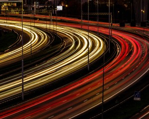 Vele koplampen en achterlampen van het verkeer die in de avond als een sliert over de A16 bij de Van Brienenoordburg slingeren