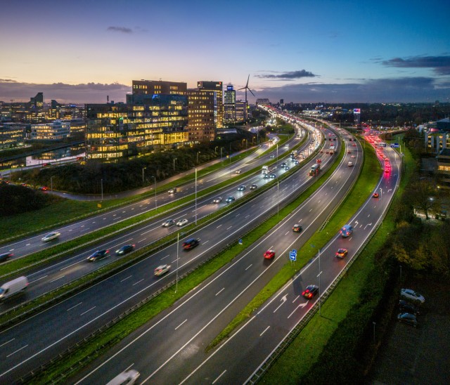 Birds eye view van de verlichte A16 snelweg rond de van Brienenoordbrug waar in de avond verkeer over heen rijdt